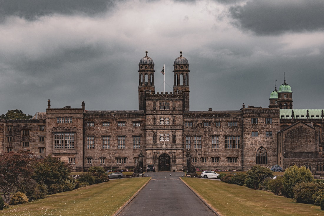 Imposing stone mansion with twin towers and a cloudy sky.