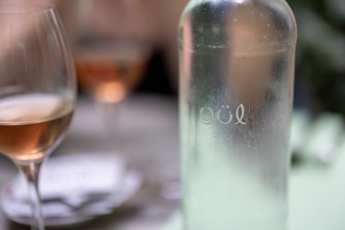 A close up of a wine glass and a bottle