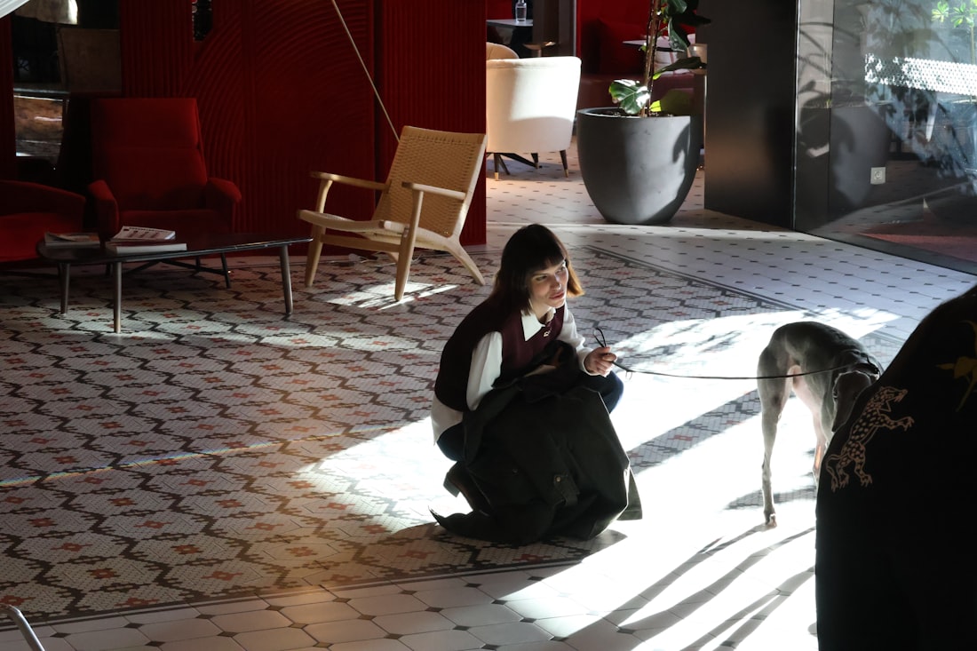 Girl and dog sitting in a sunlit room.