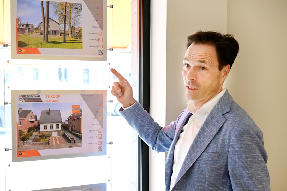 Man pointing at property listings displayed in a window.