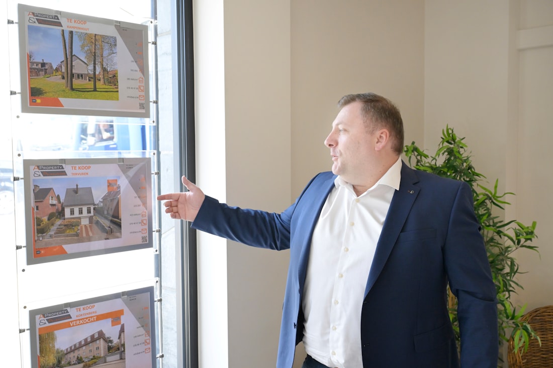 Businessman points at property listings in a window.